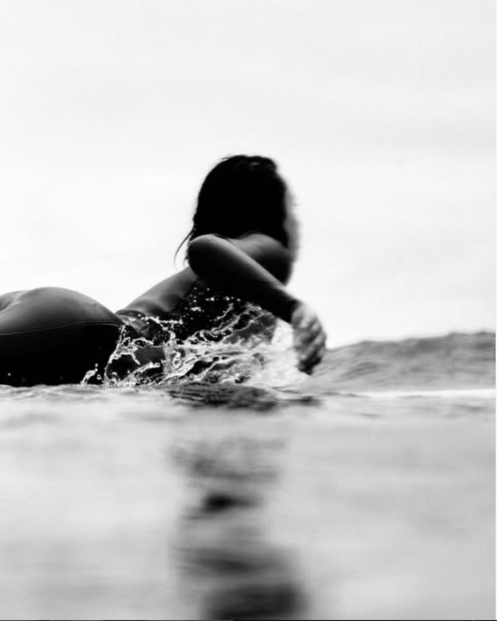 Surfer paddling out through the water
